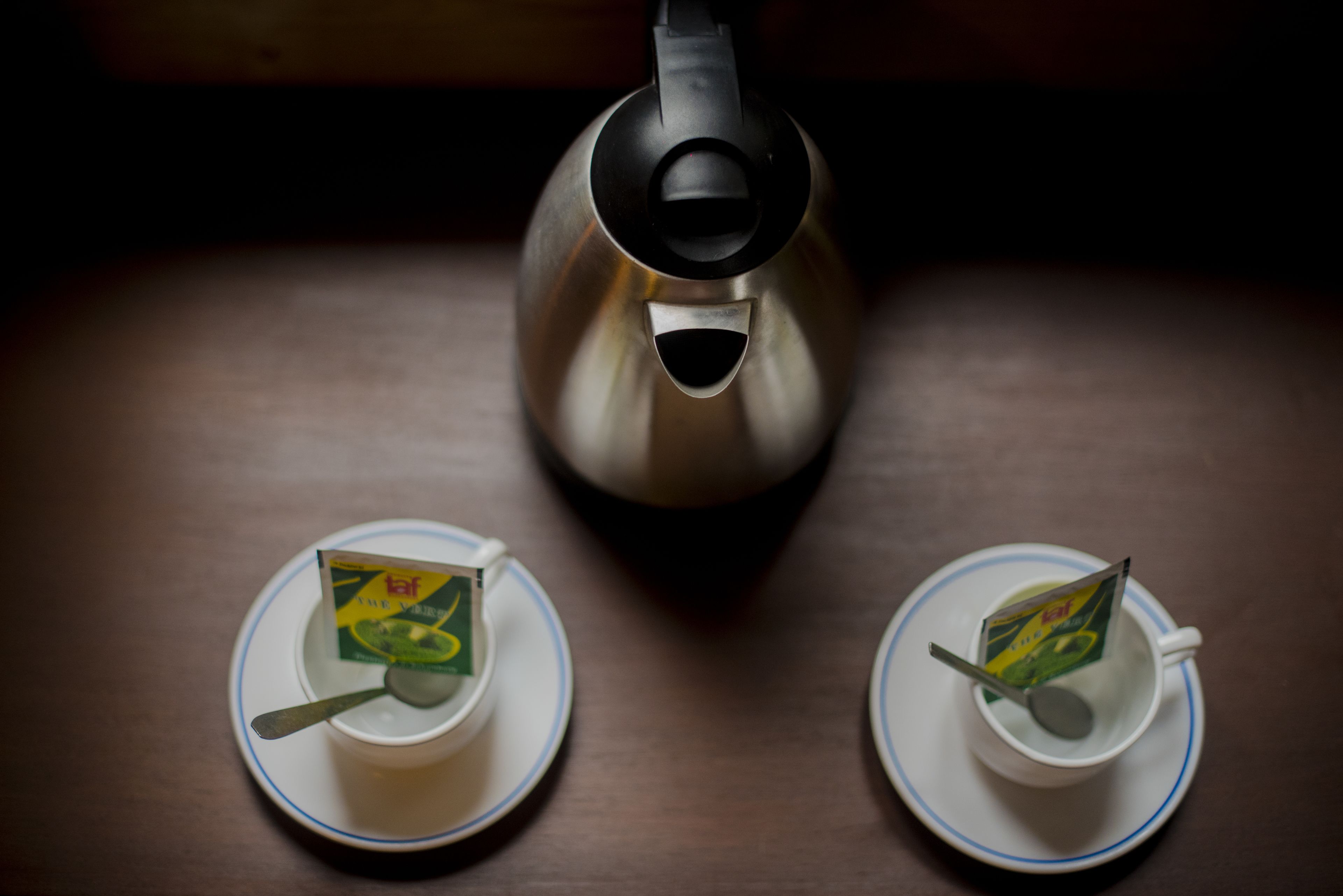 Two teacups with tea bags on a table.
