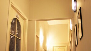 A narrow hallway with a door at the end, a bench on the left, and framed pictures on the walls. - Al Passetto St. Peter's bike (Rome)