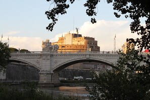 A stone bridge with statues and a view of a large building across a river. - Al Passetto St. Peter's bike (Rome)
