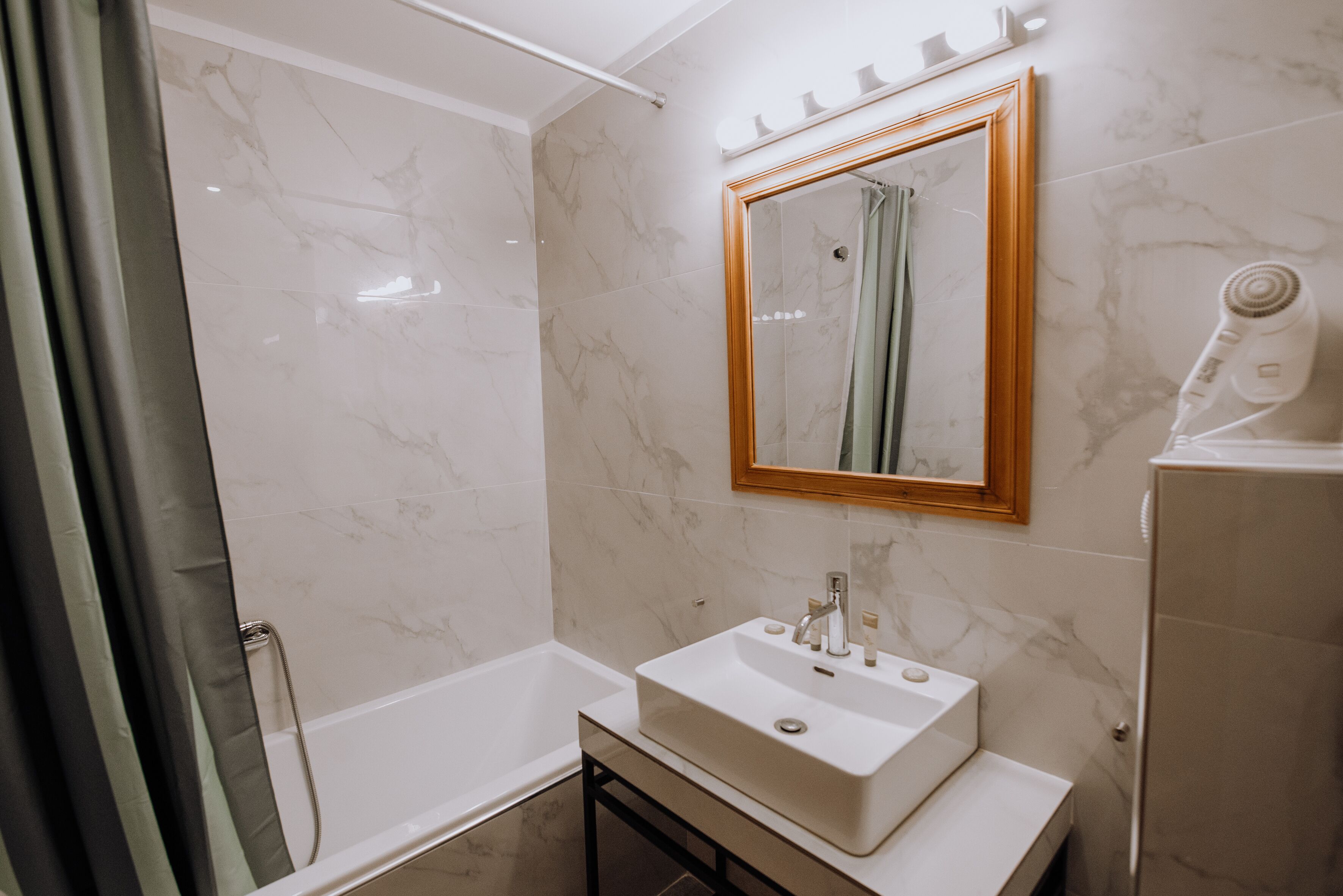 Un baño moderno con lavamanos, espejo y ducha blancos.