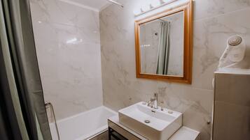 Un baño moderno con lavamanos, espejo y ducha blancos.