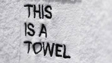 Primer plano de una etiqueta en una toalla blanca con el texto "THIS IS A TOWEL" y "PETITPALACE WOTELITY".