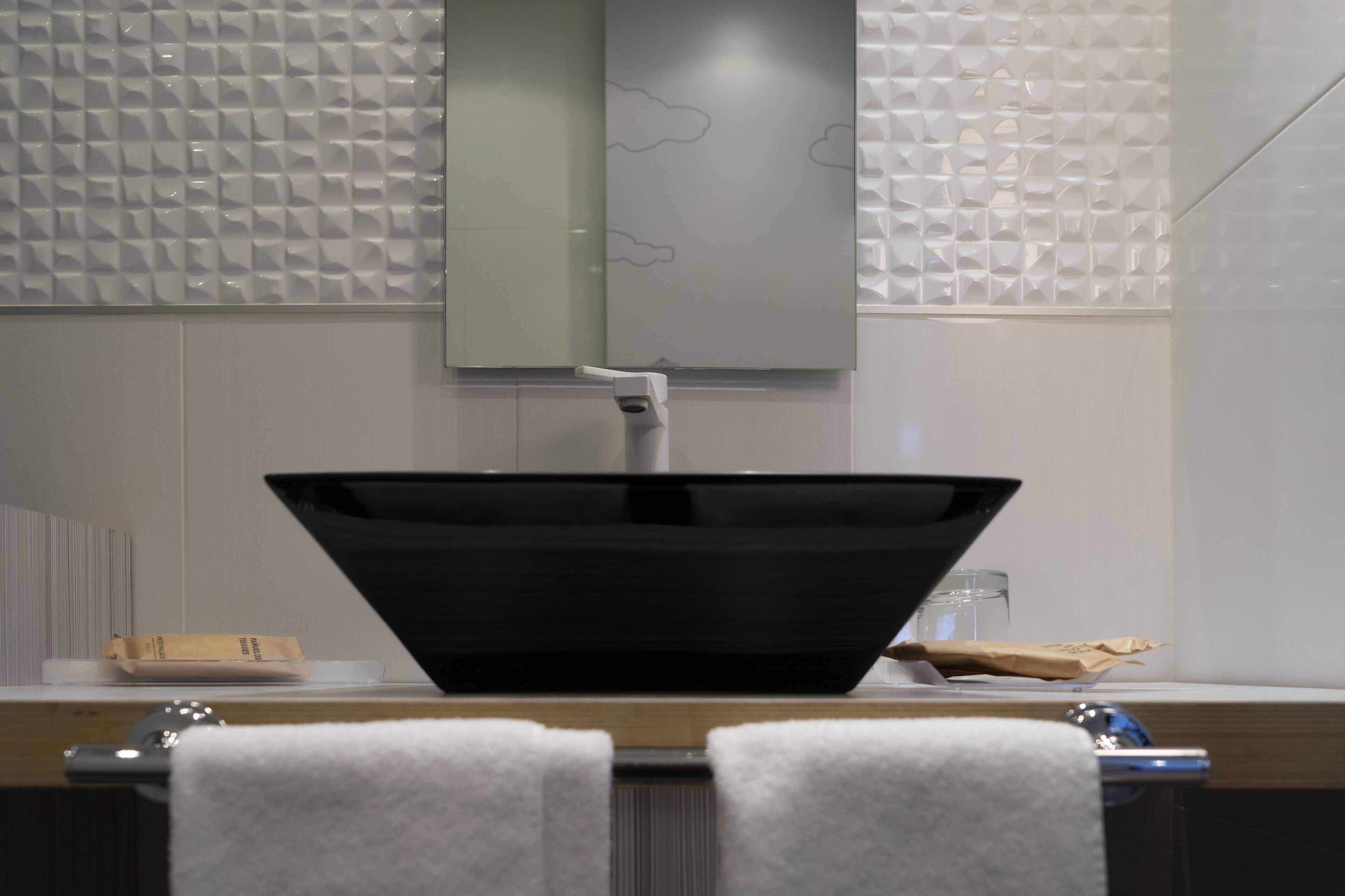 A bathroom with a modern sink, a mirror, and a towel rack.