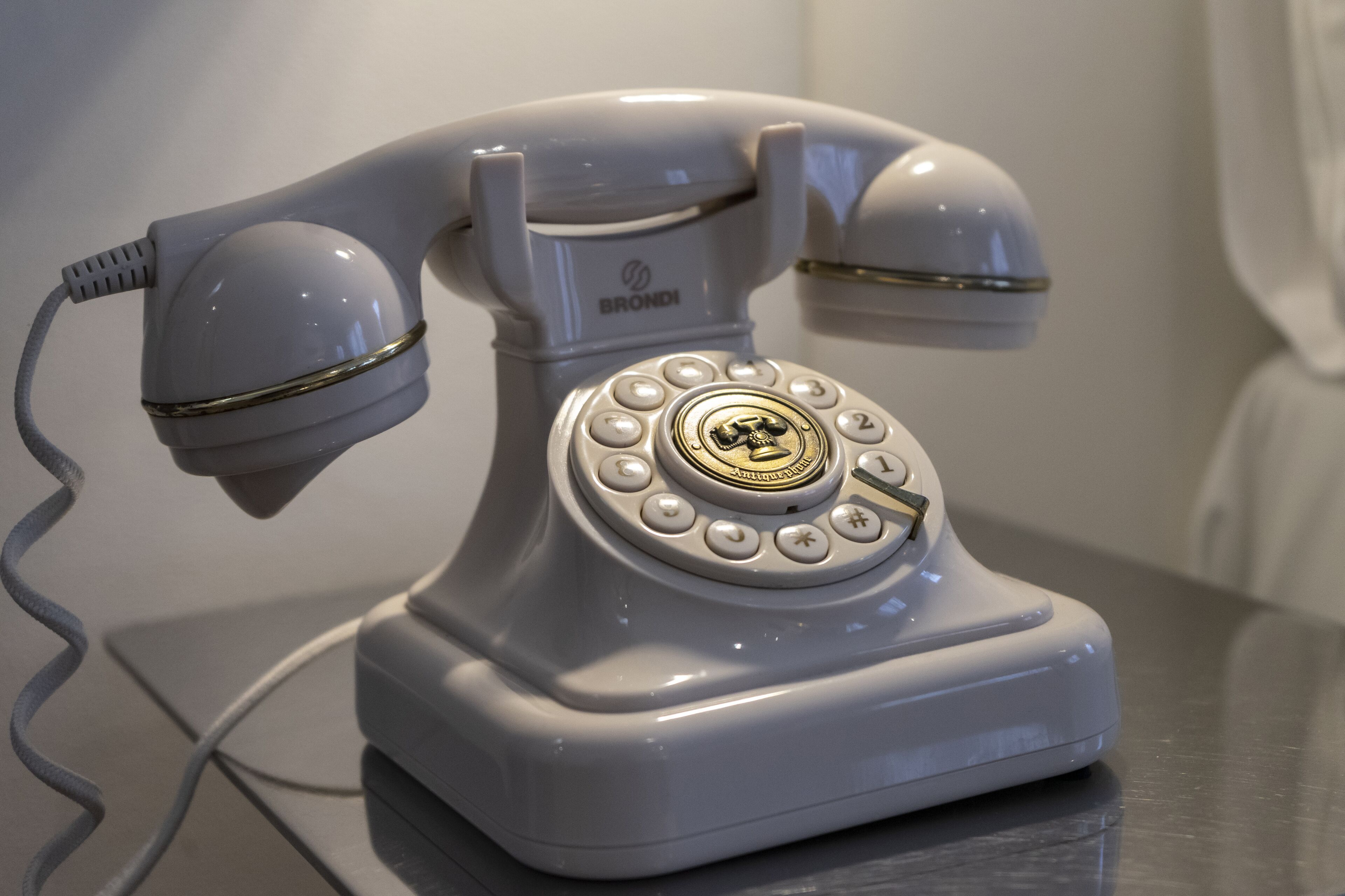 Un teléfono antiguo con disco giratorio y cable, sobre una superficie metálica.