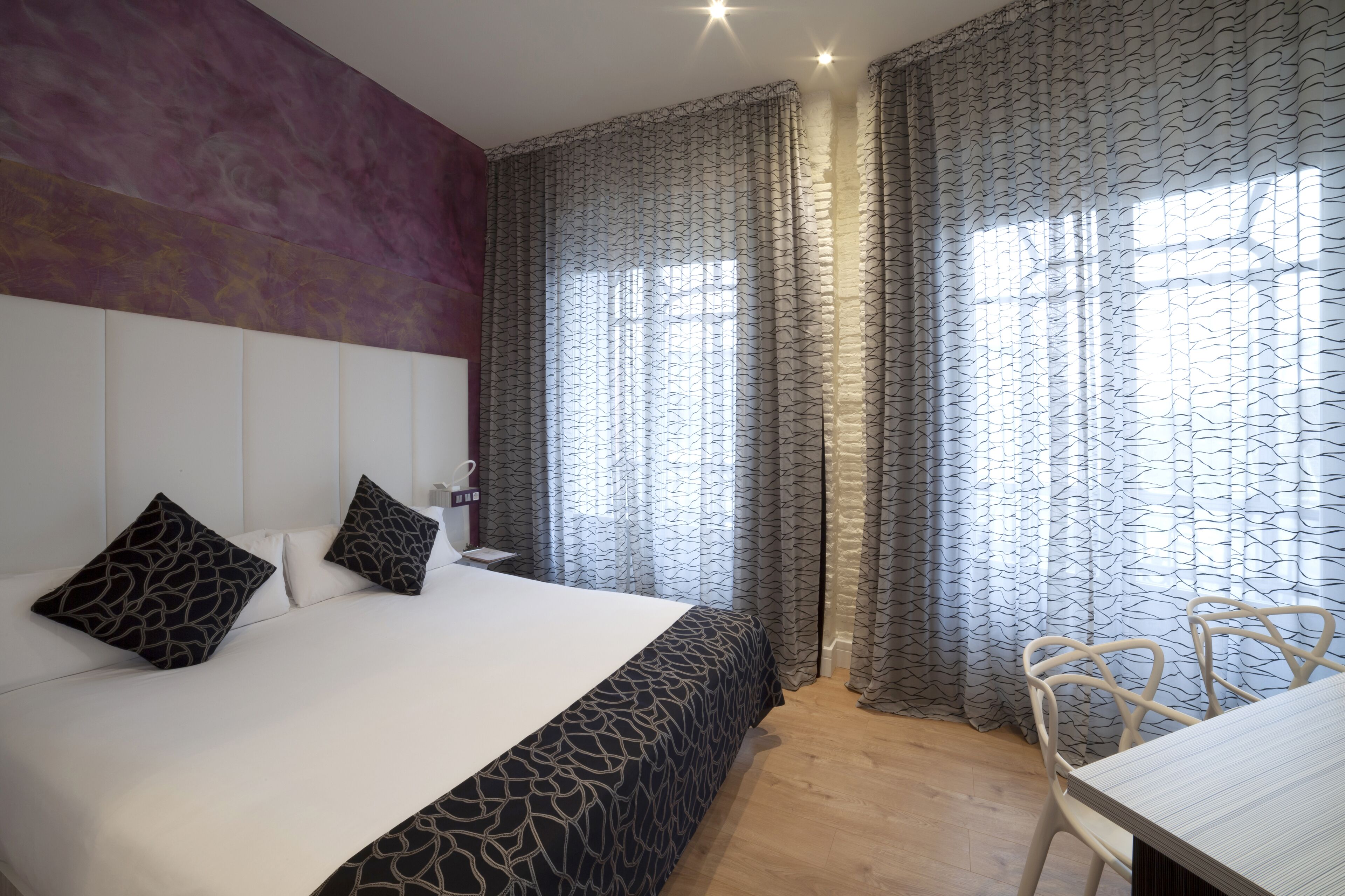 A modern hotel room with a large bed, a desk, and a chair.
