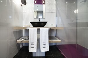 Un bagno moderno con un lavabo nero a incasso, un mobile bagno in legno e due asciugamani appesi a un portasciugamani.