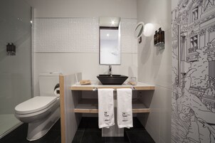 A modern bathroom with a toilet, sink, and mirror. There are two towels hanging on the towel rack.