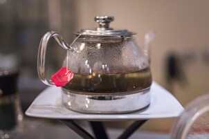 Una teiera in acciaio inossidabile con un'etichetta rossa su un vassoio bianco.