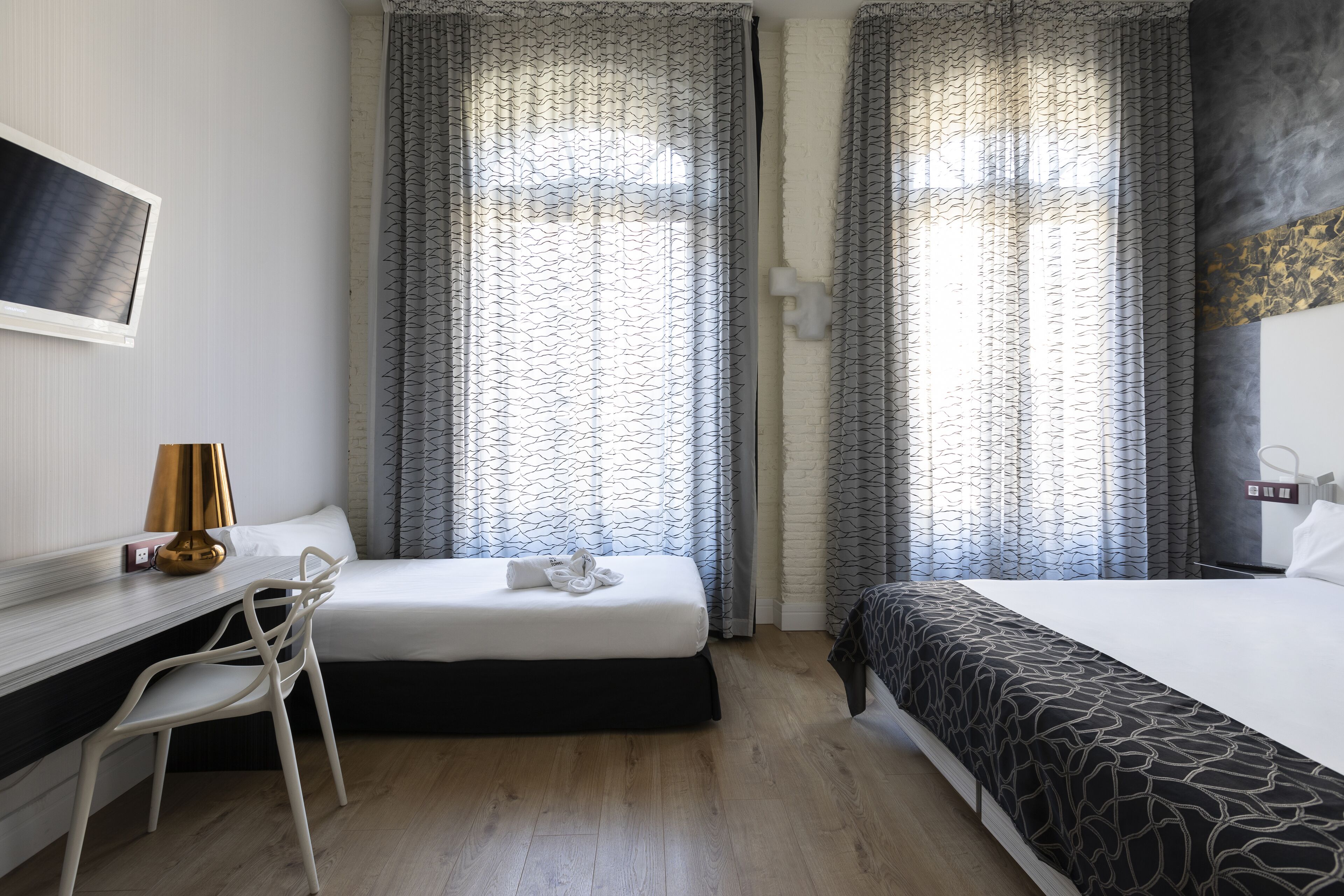 A hotel room with a bed, a desk, and a chair.