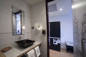 Ein modernes Badezimmer mit einem schwarzen Waschbecken, einem runden Spiegel und einer Wandleuchte.