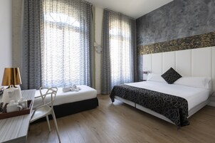 Una camera d'albergo con un letto, una scrivania con una lampada e una sedia.
