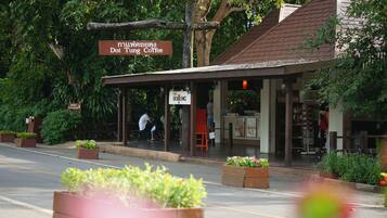 A coffee shop named "Doi Tung Coffee" with outdoor seating and a covered area.