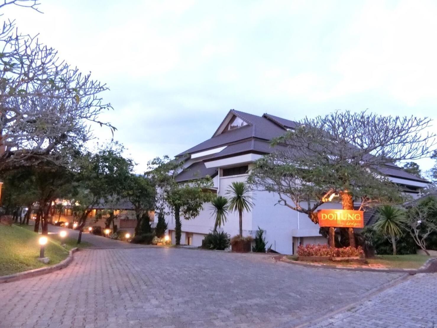 A hotel entrance with a paved driveway leading to a building with a sloped roof.