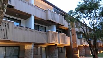 A multi-story hotel with balconies, stone pillars, and a well-maintained lawn.