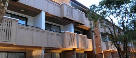 A multi-story hotel with balconies, stone pillars, and a well-maintained lawn.