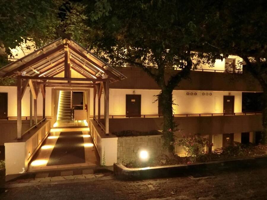 Un edificio con un acceso cubierto, una escalera que lleva a la entrada principal y varias puertas en el nivel superior.
