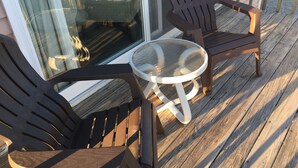 A wooden deck with two Adirondack chairs and a small round table. - Beachfront White Sands (North Truro)