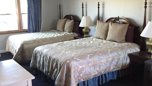 A hotel room with two beds, a small table, and a window with curtains. - Beachfront White Sands (North Truro)