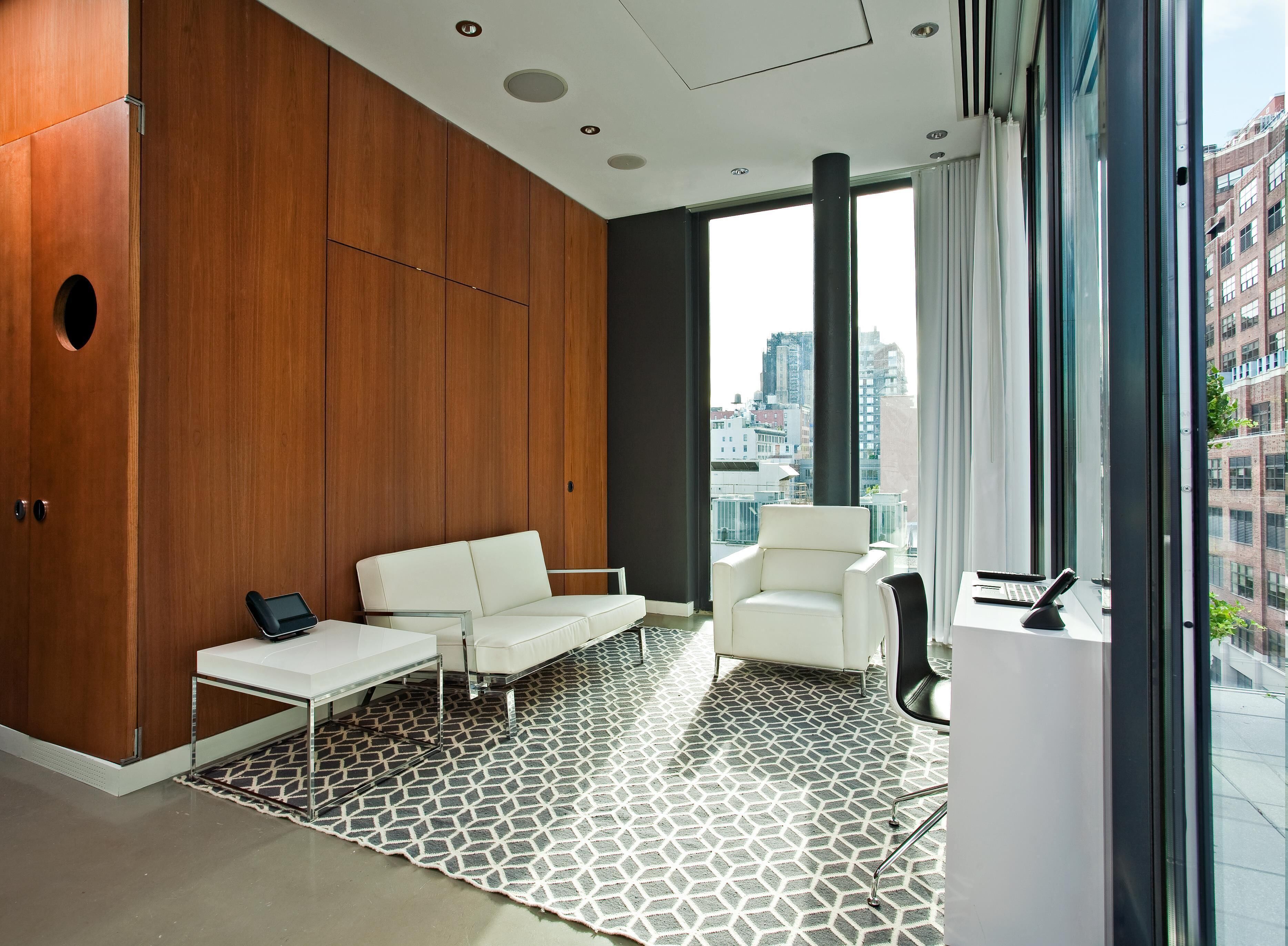 A modern living room with a white sofa, a white armchair, and a patterned rug.