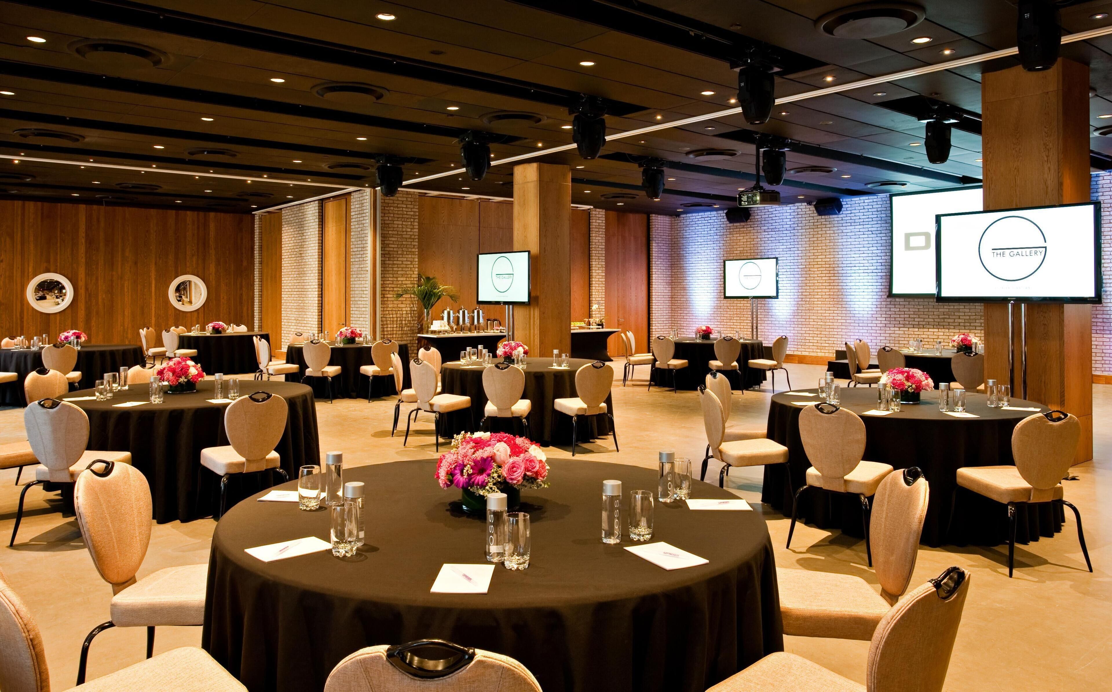 A conference room with multiple tables, chairs, and presentation screens.