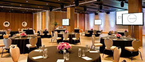 A conference room with multiple tables, chairs, and presentation screens.