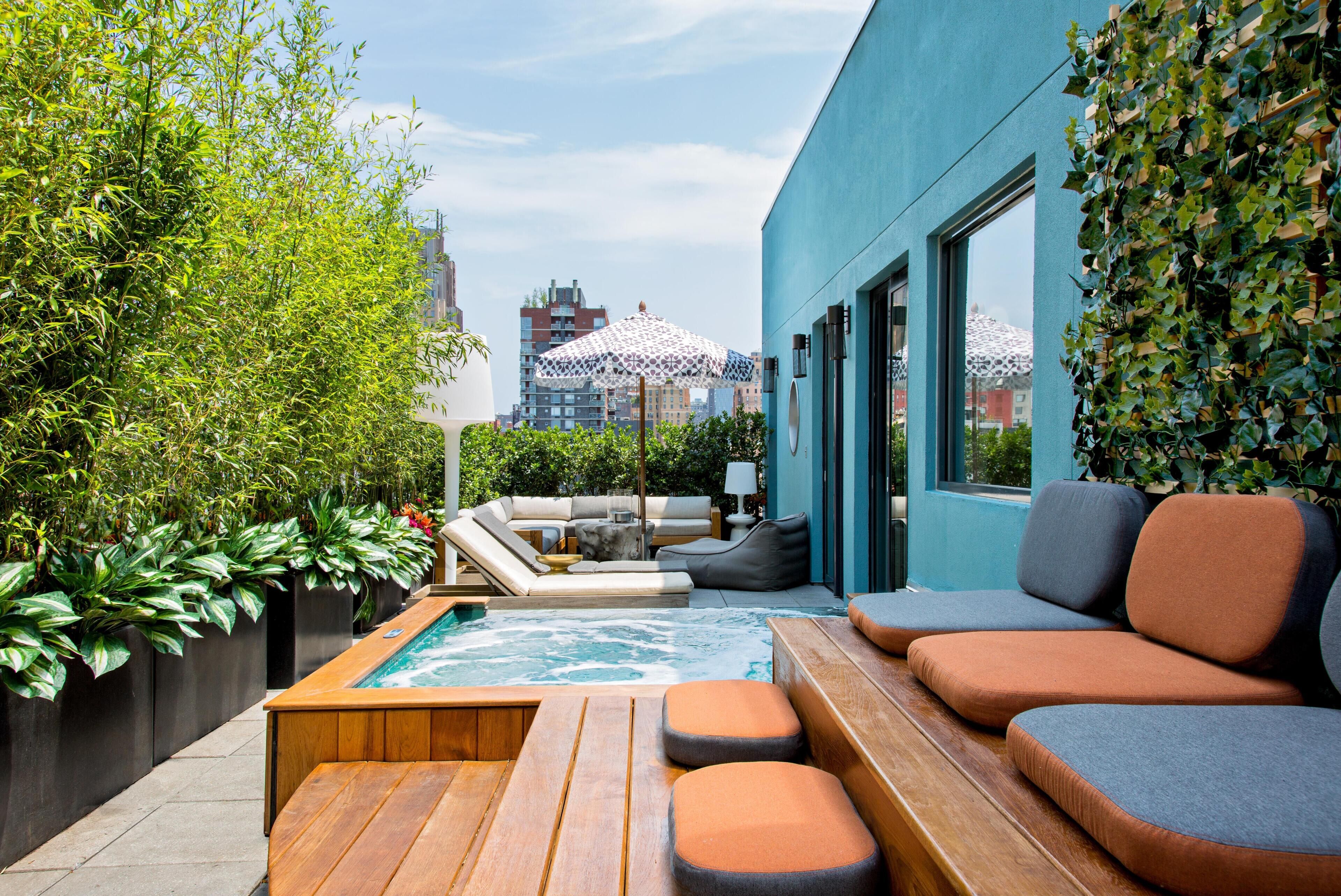 Terraza en la azotea con jacuzzi, zona de estar y abundante vegetación.