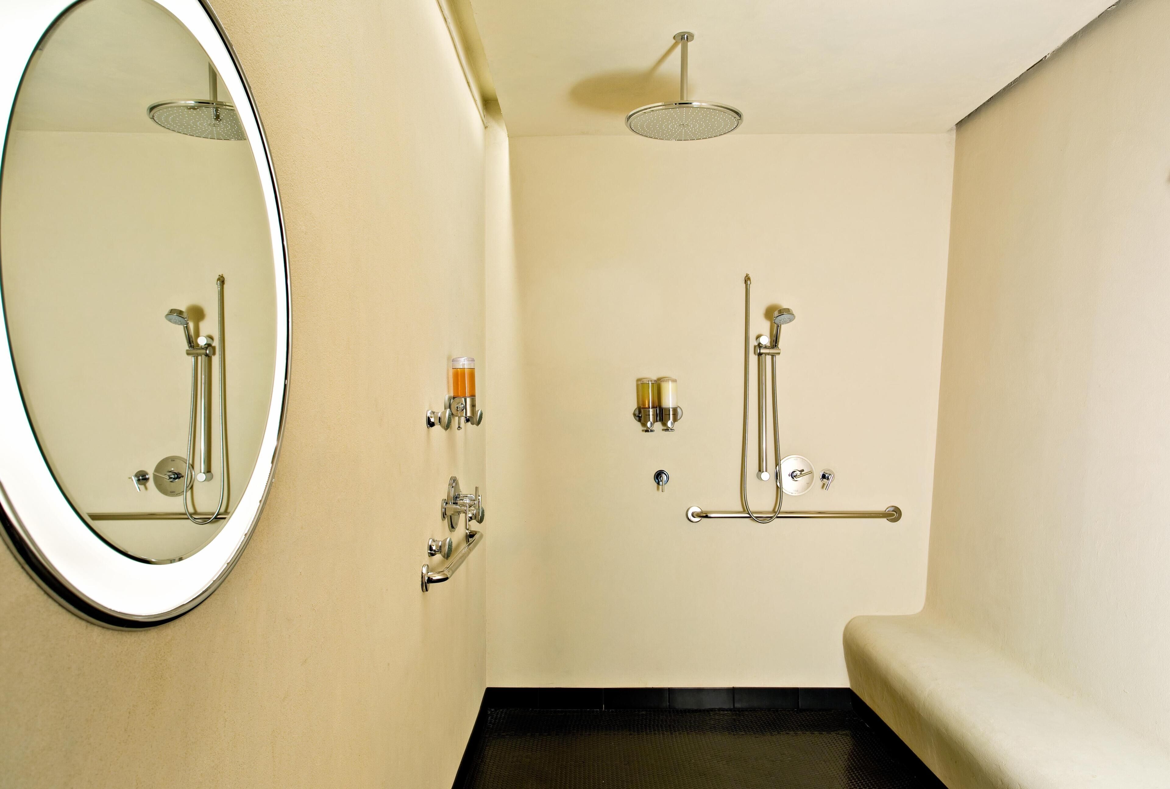 A bathroom with a round mirror, a shower, and a toilet.