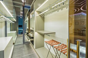 A modern hotel lobby with a central seating area, a coat rack, and a glass partition.
