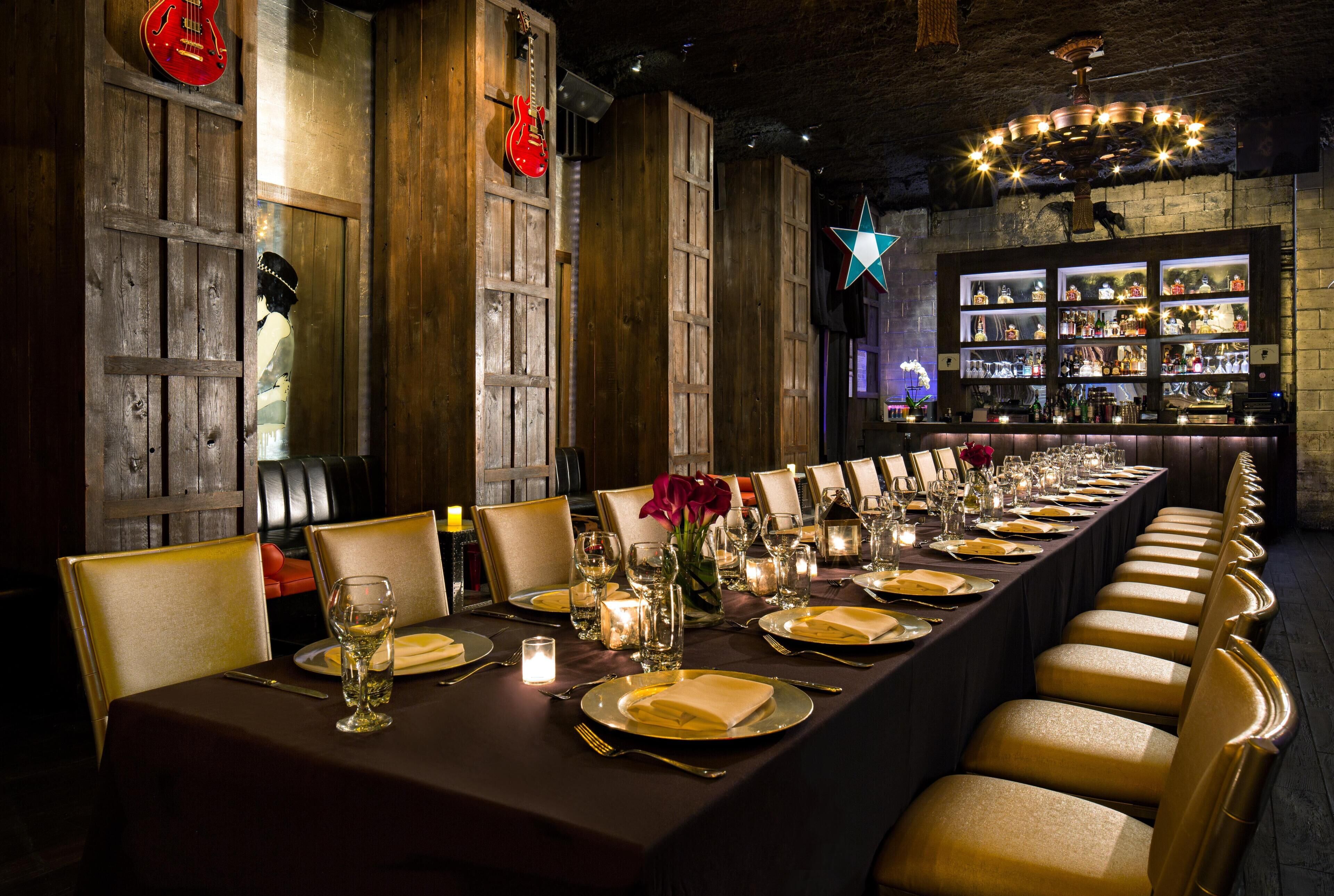 A long dining table set with multiple chairs, candles, and wine glasses, indicating a formal dining setting.