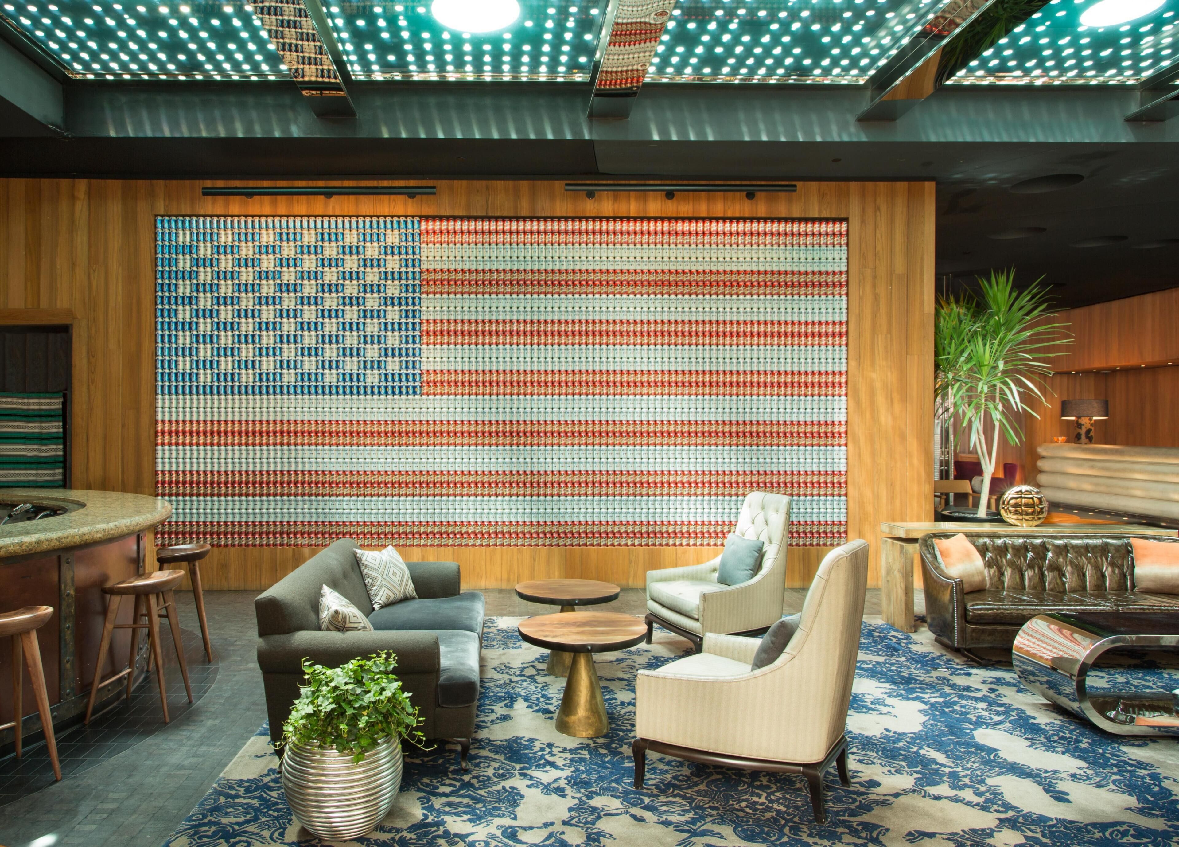 Una habitación con un tapiz grande de la bandera estadounidense, una zona de bar y asientos sobre un rug con diseño.