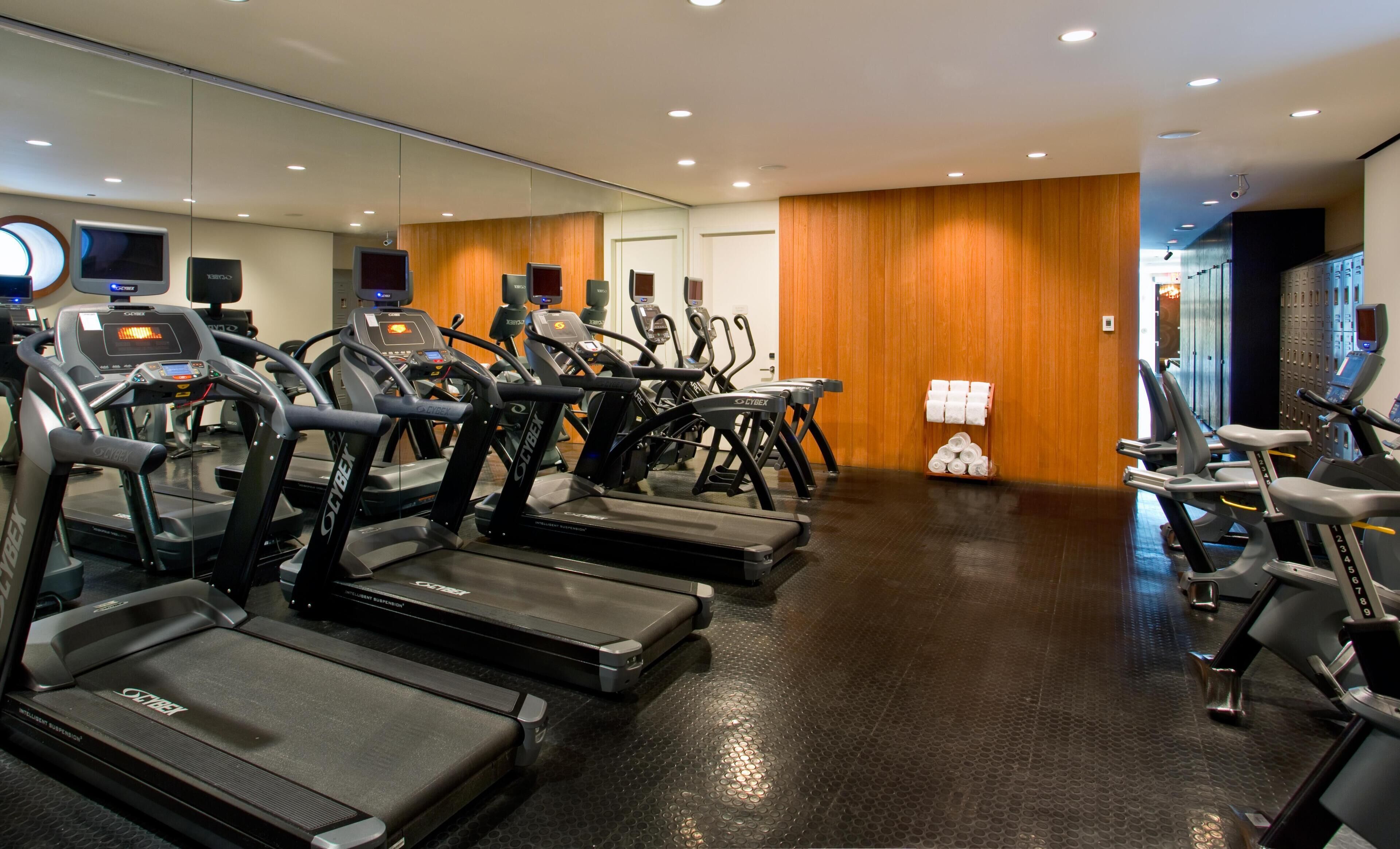 A gym with multiple treadmills, exercise bikes, and a mirrored wall.