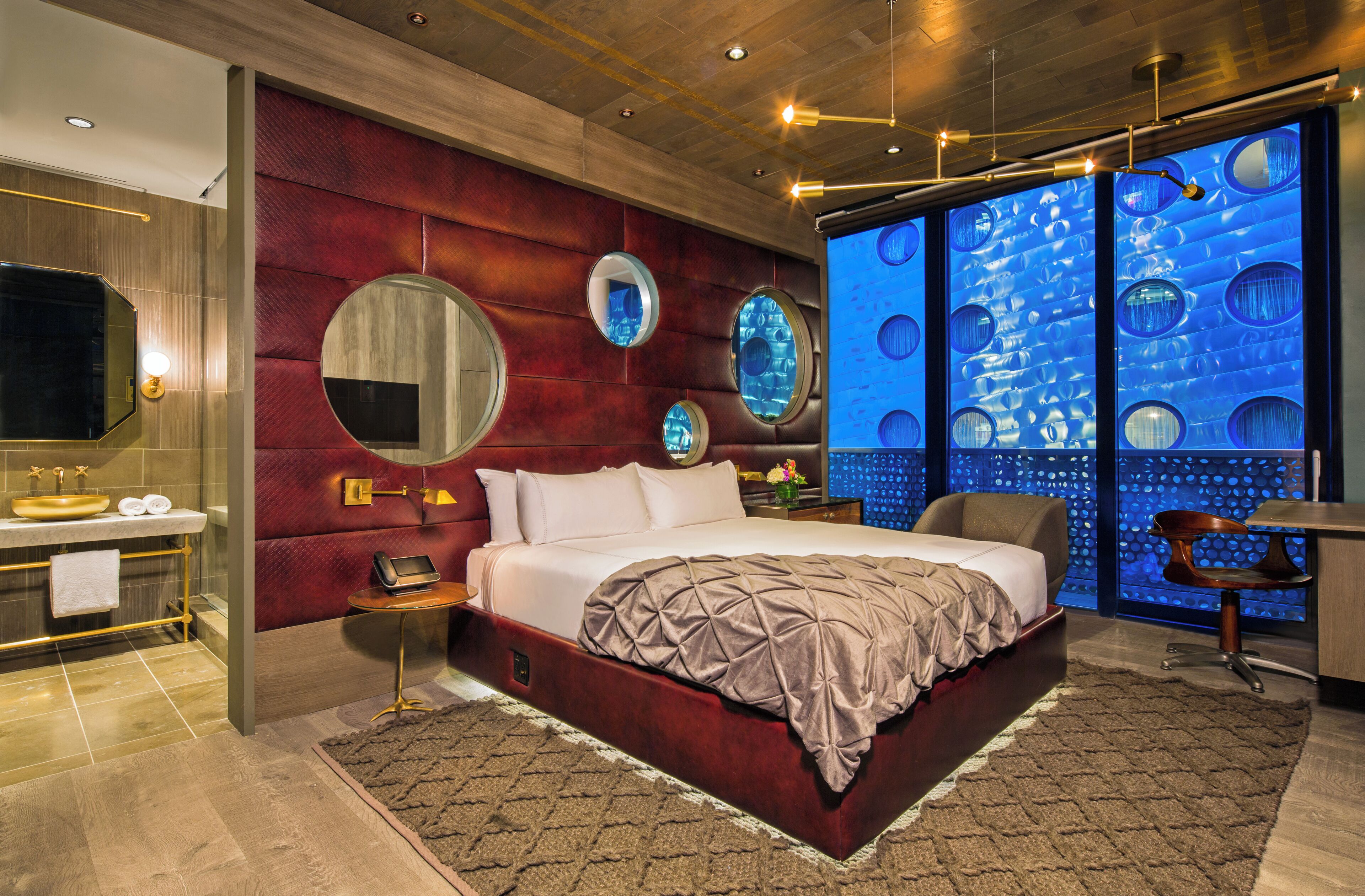Een moderne slaapkamer met een groot bed, een kaptafel met spiegel en een opvallende blauwe wanddecoratie.
