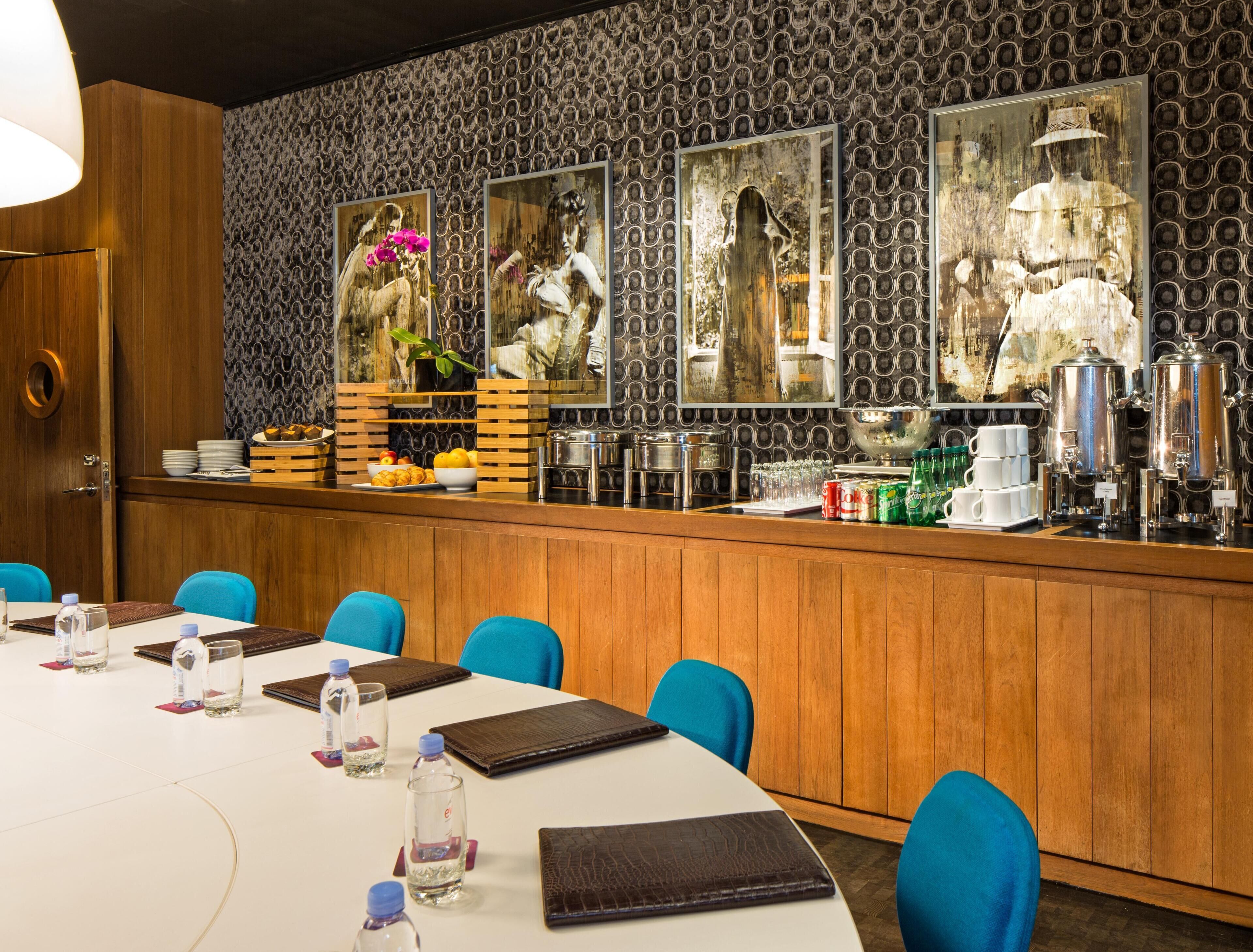 A restaurant with a long counter, blue chairs, and a variety of food and drink items.