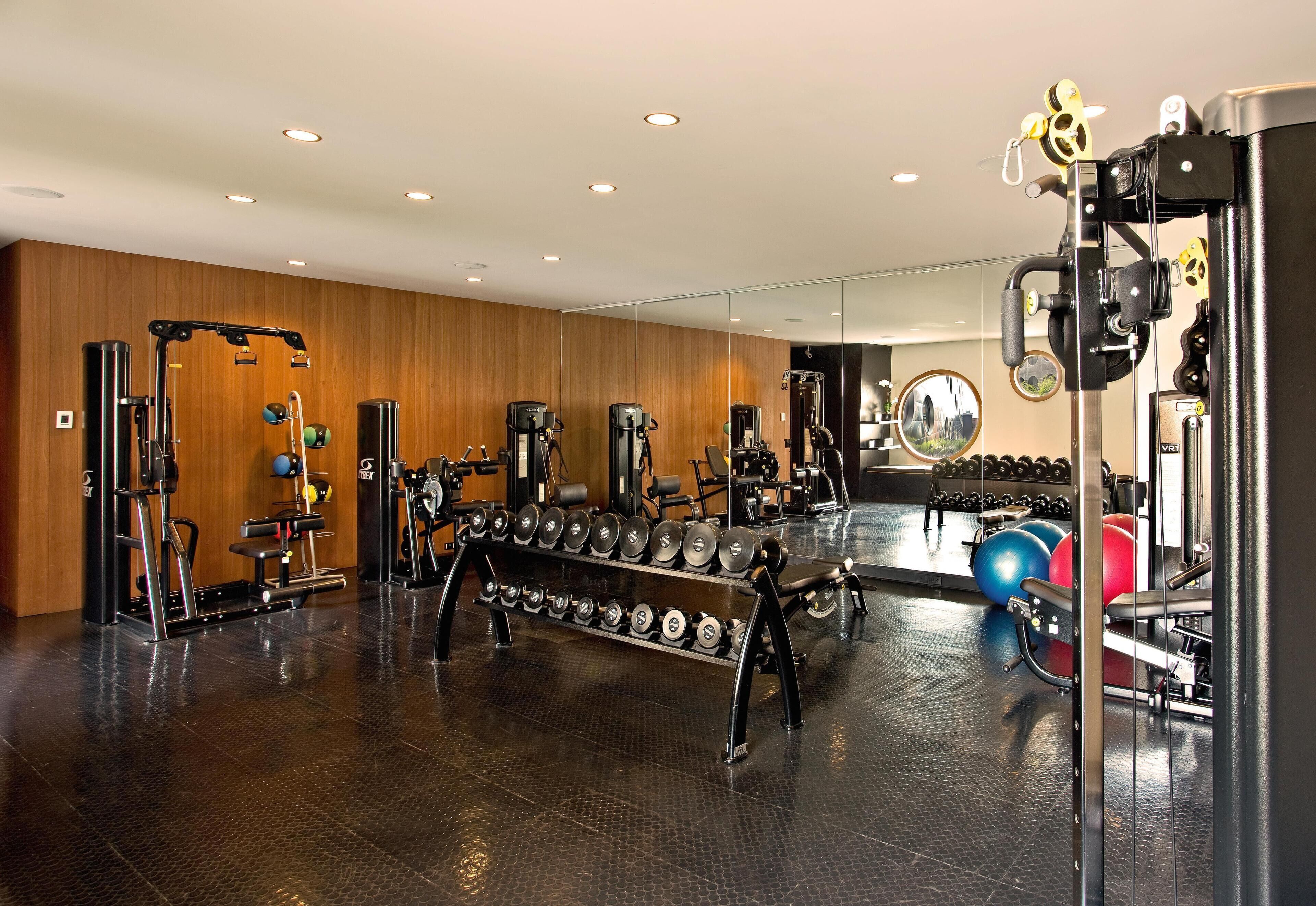 A gym with various exercise equipment, including dumbbells, a bench press, and a squat rack.