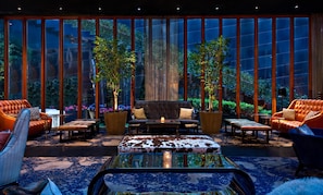 A spacious lounge with leather sofas, a coffee table, and large windows offering a view of the outdoors. - Dream Downtown, by Hyatt (New York)