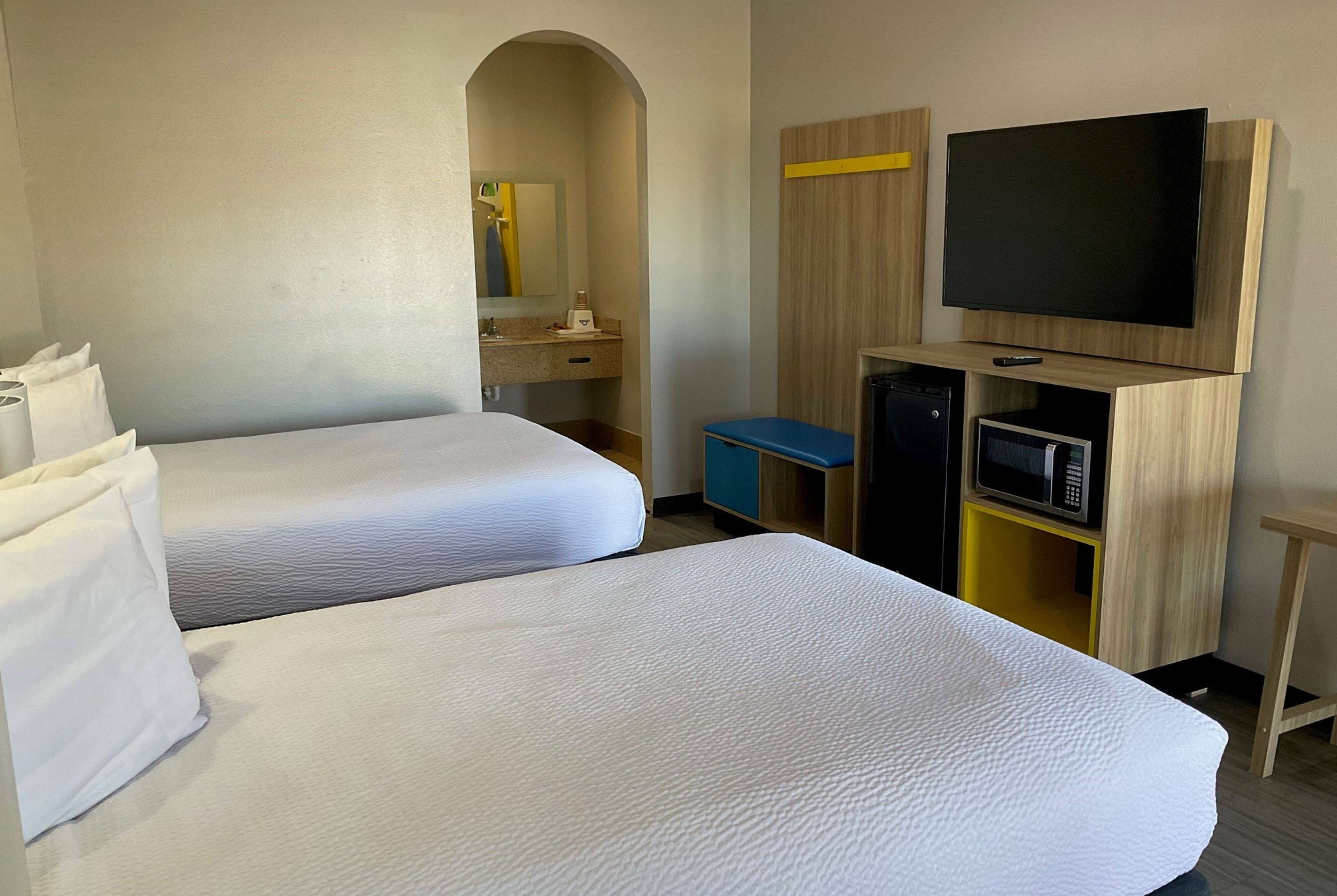 Une chambre d’hôtel avec deux lits, une télévision, un four à micro-ondes et un petit placard.
