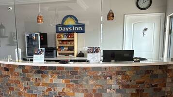 A reception desk with a Days Inn sign, a clock, and a decorative door with a feather.