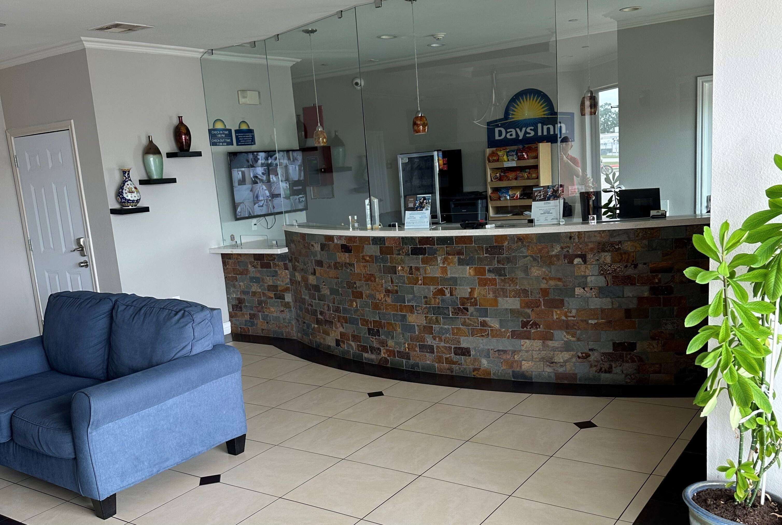 A reception area with a stone counter, a blue sofa, and a 'Days Inn' sign.