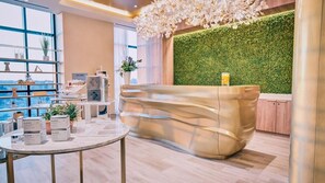 A modern reception area with a green wall, a reception desk, and a view of the city through large windows. - Wind Creek Bethlehem (Bethlehem)