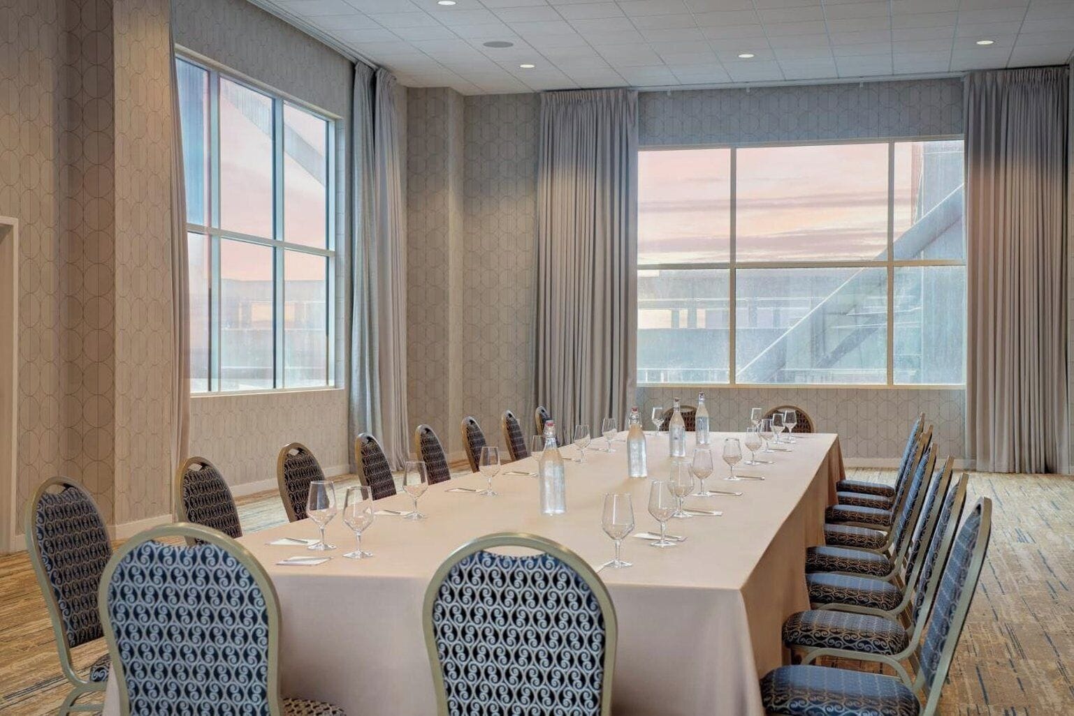 A conference room with a long table, chairs, and large windows with a view.