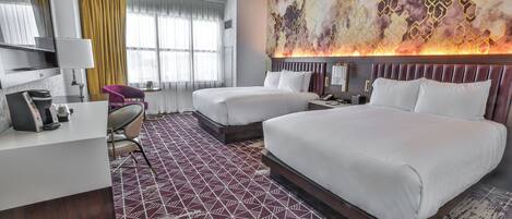 Ein Hotelzimmer mit zwei Betten, einem Schreibtisch, einem Stuhl und einem großen abstrakten Gemälde an der Wand.