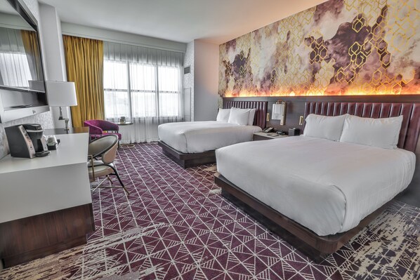 A hotel room with two beds, a desk, a chair, and a large abstract painting on the wall.
