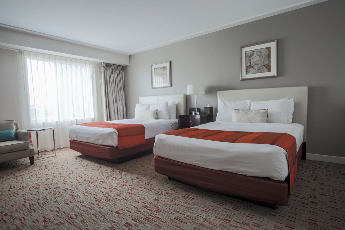 A hotel room with two beds, a sofa, a small table, and artwork on the walls.
