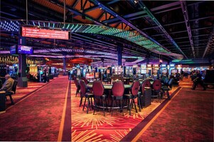 Un casino con varias mesas de juego y un pasillo alfombrado de color rojo.