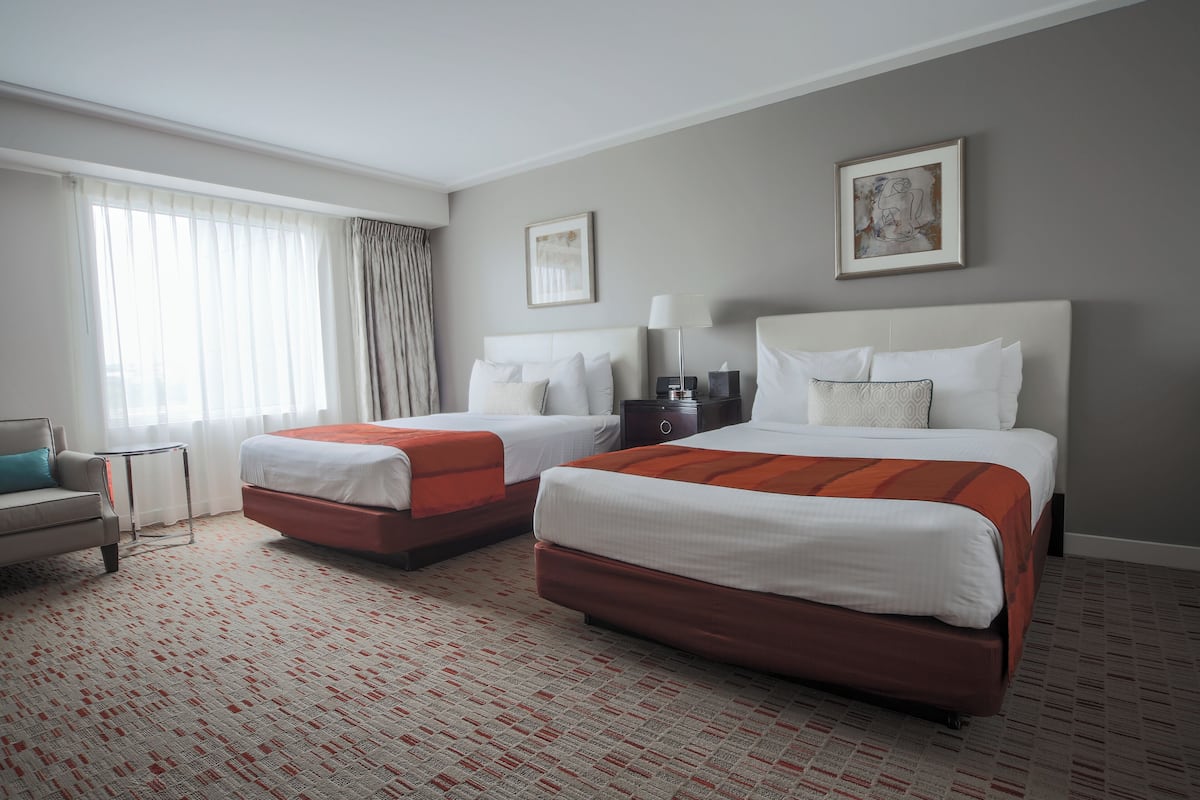 Habitación de hotel con dos camas, un sofá, una mesita y obras de arte en las paredes.