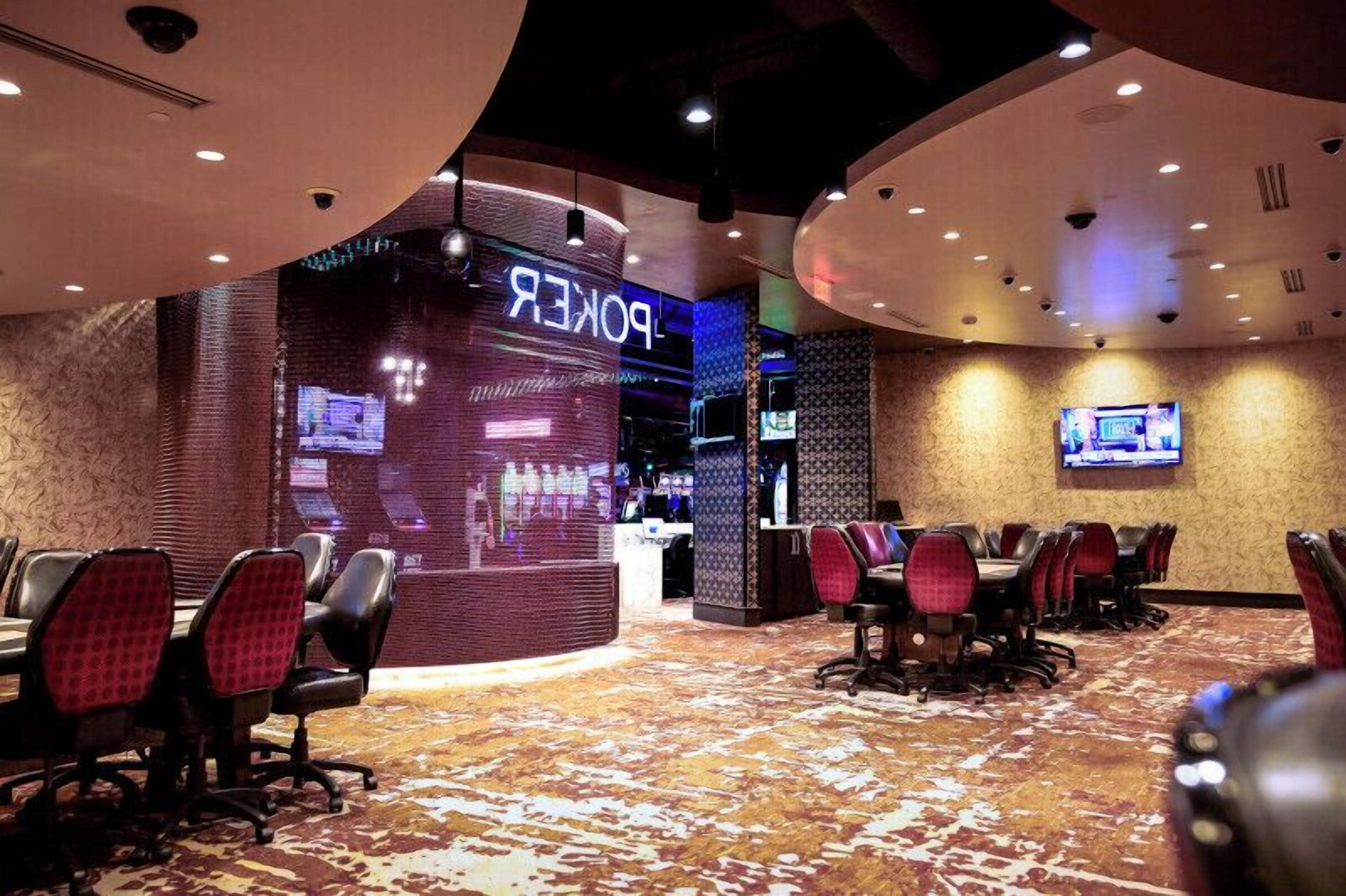A hotel lobby with a poker table area, a reception desk, and a television screen.