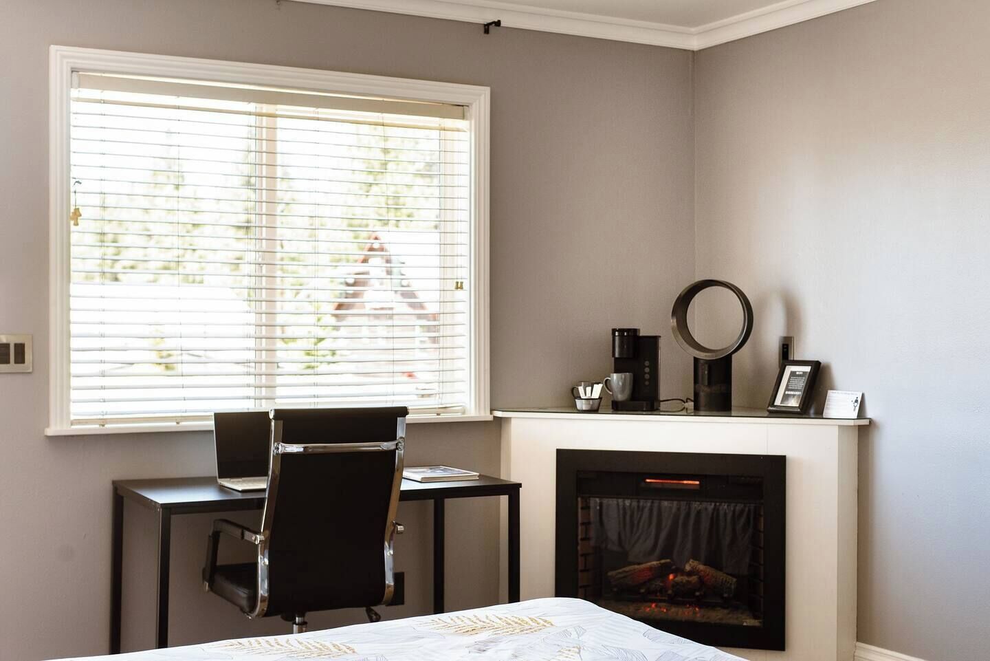 A bedroom with a desk, chair, and a fireplace.
