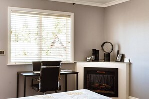 A bedroom with a desk, chair, and a fireplace.