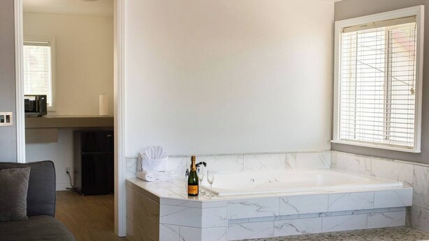 Ein modernes Badezimmer mit einer Marmortonne, einer Champagnerflasche und einem Handtuch auf der Ablagefläche.