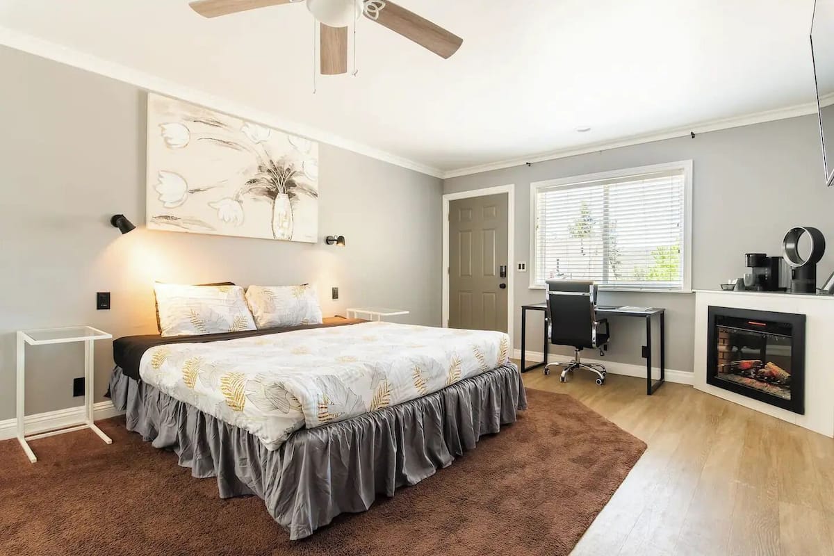 Une chambre à coucher comprenant un lit, un bureau, une chaise, une cheminée et un ventilateur de plafond.